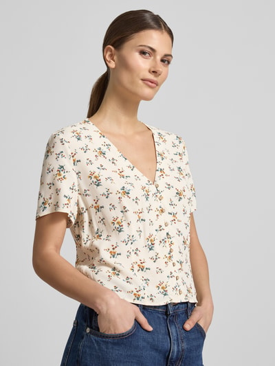 Kobiece model nosi bluzkę Slim Fit Bluse aus reiner Viskose od Jake*s Casual z wiskozy, krój slim fit, kwiatowy nadruk na całej powierzchni, dekolt w serek, z krótkim rękawem, listwa guzikowa, długość tyłu w rozmiarze 36: 50 cm, długość rękawów w rozmiarze 36: 20 cm, jasne kolory, subtelna struktura, widok z przodu na górną część ciała.