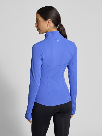 Frauenmodel trägt blaue Slim Fit Jacke mit Stehkragen Modell 'Storm' von Fabletics, glatte Struktur, Ganzkörperansicht Rückansicht