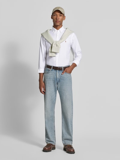 Mannenmodel draagt Regular Fit vrijetijdsoverhemd uit katoenmix van Polo Ralph Lauren, wit, lichtblauwe jeans, volledige vooraanzicht.
