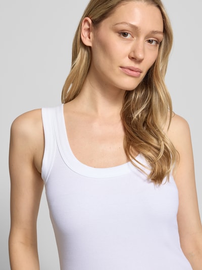 Frauenmodel trägt Tanktop mit Rundhalsausschnitt von Marc Cain aus weißem Baumwoll-Mix mit Stretch und fein gerippter Textur, Nahaufnahme Oberkörper.