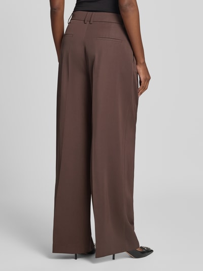 Männermodel trägt spodnie z zakładkami w pasie Wide Leg Bundfaltenhose mit Gesäßtaschen von Christian Berg Cocktail, Mieszanka materiałów z lyocellem, efekt błyszczący, kieszenie z tyłu, ciemnobrązowy kolor, szerokie nogawki, Długość wewnętrzna nogawki 82 cm, Szerokość w rozmiarze 36: 36 cm, Ganzkörperansicht Rückansicht.