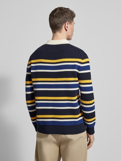 Männermodel trägt Strickpullover mit Polokragen und Label-Patch von Gant in Dunkelblau mit gelben, weißen und blauen Streifen, Baumwoll-Mix, gerader Schnitt, Rückenlänge 68 cm, Ärmellänge 66 cm, Ganzkörperansicht Rückansicht.