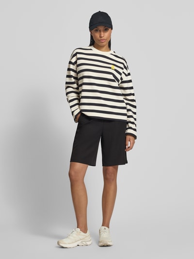 Frauenmodel trägt Oversized Sweatshirt aus reiner Baumwolle Modell 'FRANKAA BOLD' von Armedangels, Two-Tone-Optik, gestreift, Label-Patch, Logo-Stitching, Rundhals-Ausschnitt, Langarm, Materialverarbeitung Sweat, Ganzkörperansicht von vorne.