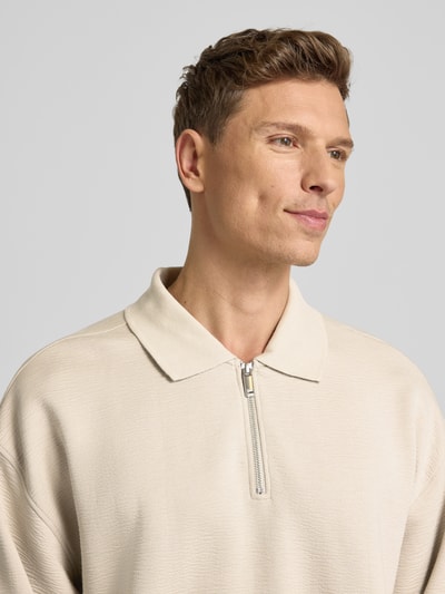 Männermodel trägt Sweatshirt mit Polokragen und Reißverschluss von CK Calvin Klein, Material-Mix mit Modal-Anteil, Strukturmuster, Relaxed-Fit, Nahaufnahme Oberkörper.