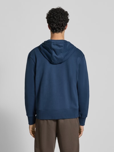 Męski model nosi Sweatjacke mit Kapuze Modell 'TAURASI' od Ellesse w luźnym kroju, bawełniany miks, granatowy kolor, widok całej sylwetki z tyłu.