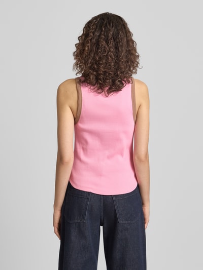 Frauenmodel trägt Slim Fit Top mit Logo-Stitching Modell 'Fiora' von OH APRIL in Rosa mit braunen Details, Strukturmuster, Ganzkörperansicht Rückansicht.