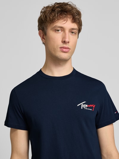Männermodel trägt Slim Fit T-Shirt aus reiner Baumwolle von Tommy Jeans in Optik: Unifarben, Label-Print, Rundhals, Ärmelform: Kurzarm, Nahaufnahme Oberkörper.