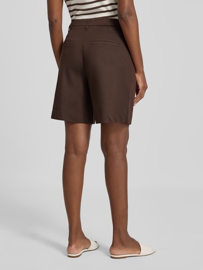 Frauenmodel trägt Bermudas mit Gesäßtaschen Modell 'HAYE' von FREE/QUENT in Braun, glatte Textur, Regular Fit, Ganzkörperansicht Rückansicht. Material-Mix mit Viskose-Anteil, Knopf- und Reißverschluss.
