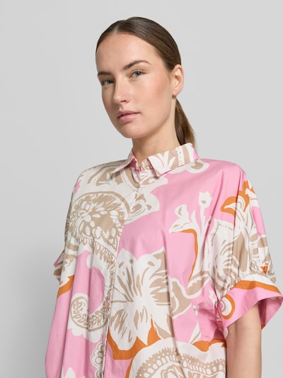 Vrouwenmodel draagt Relaxed Fit Hemdbluse mit Allover-Paisley-Print van Emily Van den Bergh in roze met paisleyprint van puur katoen, overhemdkraag, korte mouw, knoopsluiting. Close-up bovenlichaam.