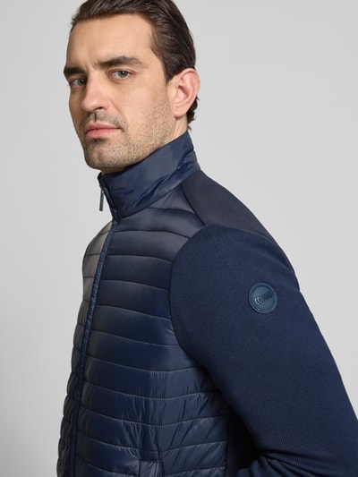 Männermodel trägt Regular Fit Jacke in Stepp-Optik von Colmar Originals in Dunkelblau mit Stehkragen, Eingrifftaschen, Zweiwege-Reißverschluss, Nahaufnahme Oberkörper. Rückenlänge 67 cm, Schulterbreite 42 cm, Brustweite 51 cm, Ärmellänge 64 cm bei Größe 50.