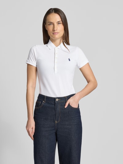 Vrouwenmodel draagt Slim Fit Poloshirt met Logo-Stitching Modell 'JULIE' van Polo Ralph Lauren, wit, katoen-elastaan mix, effen, polokraag, korte knoopsluiting, geribde mouwboorden, ruglengte maat S: 65 cm. Vooraanzicht volledige lichaamsopname.
