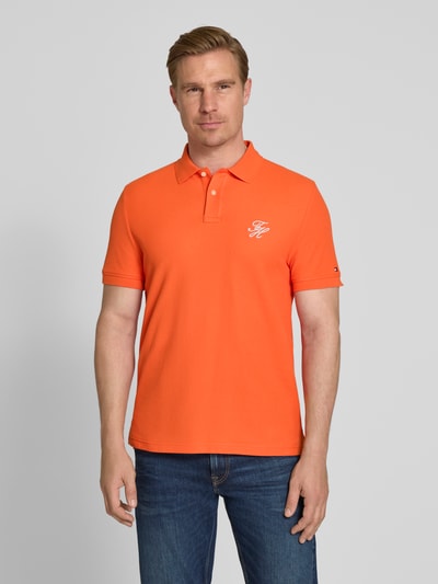 Męski model nosi Regular Fit Poloshirt aus reiner Baumwolle od Tommy Hilfiger, pomarańczowy, gładki, logo, krój regular fit, piqué, krótki rękaw, widok całej sylwetki z przodu.