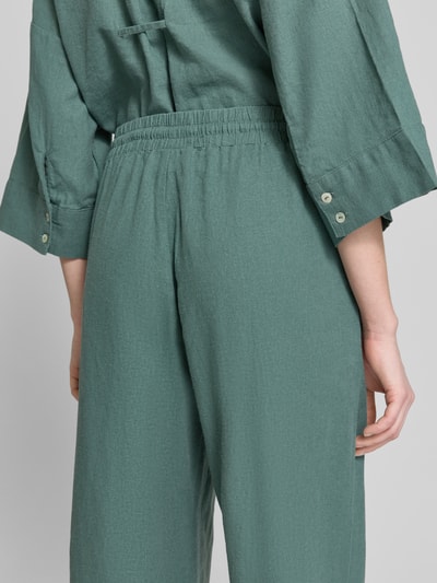 Frauenmodel trägt Wide-Leg-Pants aus Leinen-Mix mit elastischem Bund Modell 'Lava' von FREE/QUENT in Grün, Loose-Fit, Textur leicht strukturiert, Leinen-Viskose-Anteil, Kordelzug, Bundweite Größe S 41 cm, Innenbeinlänge 77 cm, Ganzkörperansicht Rückansicht.