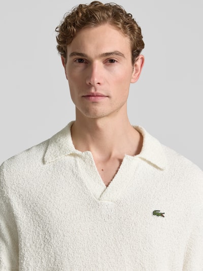 Männermodel trägt Regular Fit Poloshirt aus Baumwoll-Mix von Lacoste, Optik: Unifarben, Label-Patch, Polokragen, V-Ausschnitt, Ärmelform: Kurzarm, Materialverarbeitung: Bouclé, Nahaufnahme Oberkörper.