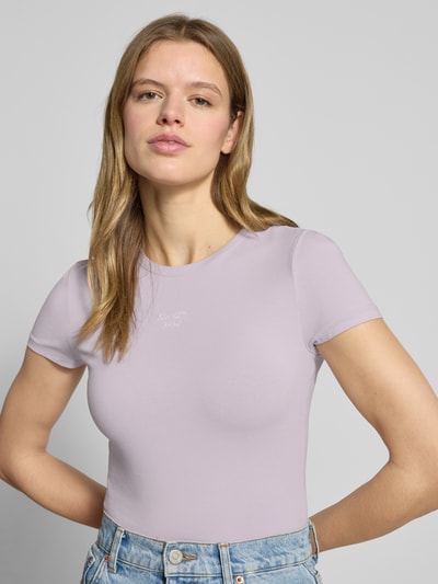Frauenmodel trägt Slim Fit T-Shirt mit Logo-Stitching Modell 'Downtown' von Review in Flieder, elastischer Baumwoll-Mix, Nahaufnahme Oberkörper.