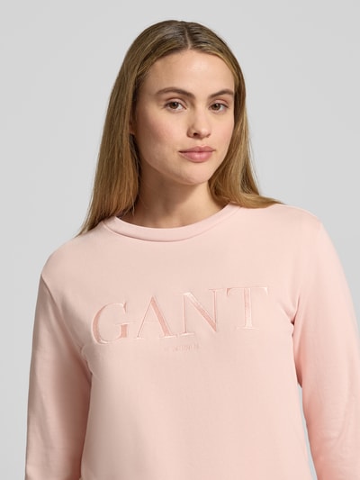 Frauenmodel trägt Sweatshirt mit Label-Stitching und Rundhalsausschnitt von Gant in zartem Rosa, reine Baumwolle, Nahaufnahme Oberkörper.