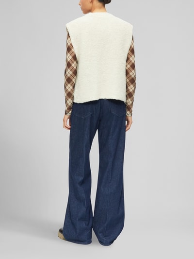 Männermodel trägt Regular Fit Strickweste mit Woll-Anteil von s.Oliver RED LABEL in Beige, kombiniert mit karierter Bluse und weiter Jeans, Ganzkörperansicht Rückansicht.