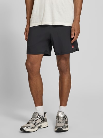 Mężczyznamodel nosi szorty mit Logo und Eingrifftaschen von Under Armour, czarny kolor, krój regular fit, wpuszczane kieszenie, elastyczny pas, szerokość w rozmiarze M: 38 cm, Ganzkörperansicht von vorne.