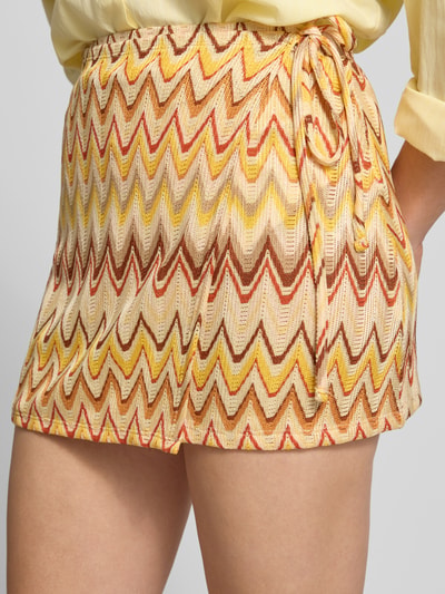 Frauenmodel trägt Minirock im Stufen-Look von Gina Tricot in Gelb, Rot und Beige, Material-Mix mit Stretch-Anteil, elastischer Bund, Nahaufnahme Oberschenkel.