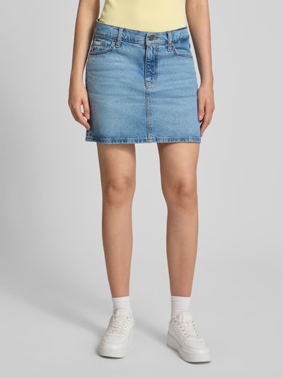 Frauenmodel trägt Jeansrock mit Eingrifftaschen von GUESS in Hellblau, gerader Schnitt, Baumwoll-Elasthan-Mix, Ganzkörperansicht von vorne.