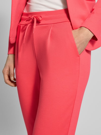 Kobiece modelka nosi Slim Fit Stoffhose mit Viskose-Anteil Modell 'Kate' von ICHI, elastyczna mieszanka materiałów, wpuszczane kieszenie, zakładki w pasie, różowy kolor, materiał gładki, tunel w pasie, szerokość w rozmiarze S: 38 cm, długość wewnętrzna nogawki: 65 cm, krój slim fit, detaliczny widok przodu, zbliżenie na biodra