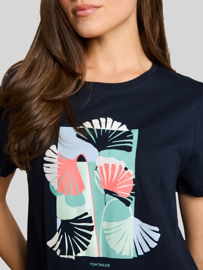 Frauenmodel trägt Regular Fit T-Shirt aus reiner Baumwolle von Tom Tailor, Optik: Unifarben, Motiv-Print-Stitching, Label-Print, Jersey, Rundhals, Kurzarm, Nahaufnahme Oberkörper.