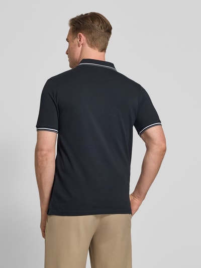 Männermodel trägt Relaxed Fit Poloshirt mit Kontraststreifen von Lindbergh aus bawełna, krój relaxed fit, wyhaftowane logo, listwa guzikowa, długość tyłu w rozmiarze M: 67 cm, kolor czarny z białymi paskami w kontrastowym kolorze, widoczna gładka faktura, Ganzkörperansicht Rückansicht.