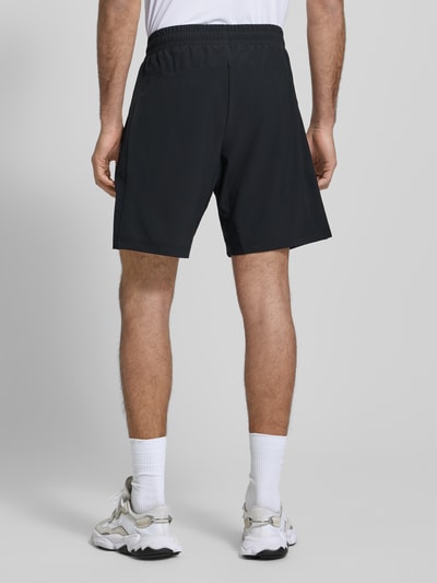 Männermodel trägt Shorts mit elastischem Bund und Logo von EA7 Armani, Material-Mix mit Stretch-Anteil, Regular-Fit, Eingrifftaschen, Ganzkörperansicht Rückansicht.
