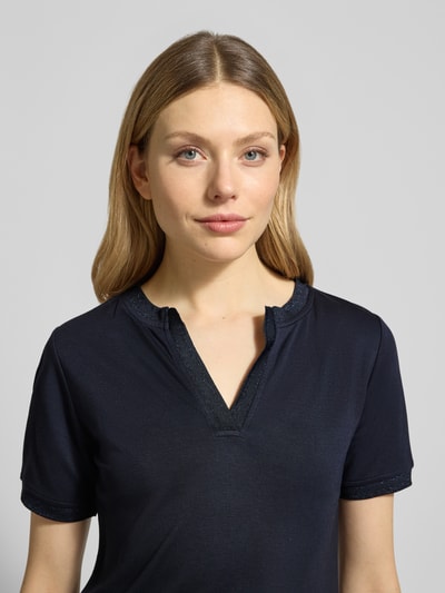 Frauenmodel trägt T-Shirt mit V-Ausschnitt von More & More, dunkelblau, schimmernde Abschlüsse, Modal-Elasthan-Mix, Nahaufnahme Oberkörper.