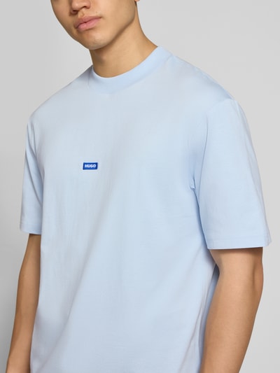 Männermodel trägt Regular Fit T-Shirt aus reiner Baumwolle Modell 'NIEROS' von Hugo Blue in Optik: Unifarben mit Logo-Detail, Rundhals, Kurzarm, Nahaufnahme Oberkörper.
