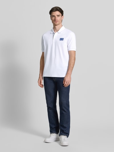 Mannenmodel draagt Regular Fit poloshirt met knoopsluiting van ARMANI EXCHANGE, mix van katoen en elastaan, labelprint, mouwboordjes, ruglengte maat M 70 cm, voorkant volledig te zien.