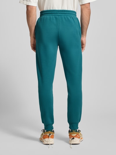 Männermodel trägt Sweatpants mit elastischem Bund von PUMA PERFORMANCE aus Baumwoll-Mix mit Label-Stitching, Rückansicht, Lockerer-Schnitt, französische Eingrifftaschen, Innenbeinlänge 75 cm bei Größe M. Ganzkörperansicht Rückansicht.