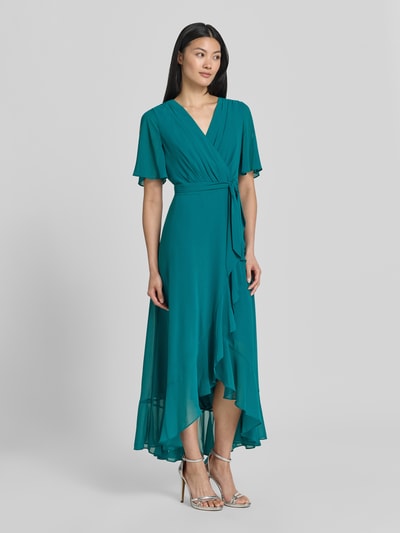 Modelka kobieca nosi 'Cocktailkleid in Wickel-Optik' od Christian Berg Cocktail, turkusowy szyfon, krój taliowany, długość midi, pasek, Szerokość w rozmiarze 36: 40 cm, długość tyłu 35 cm, długość rękawa 29 cm, widok całej sylwetki z przodu.
