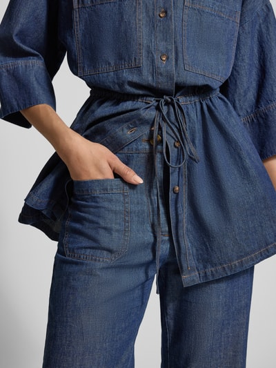 Frauenmodel trägt Flared Hose mit aufgesetzten Taschen von Jake*s Collection in dunkelblauem Denim, sichtbare Nähte, Nahaufnahme Oberkörper