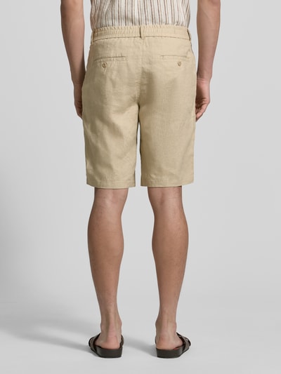Mannenmodel draagt Shorts aus Leinen mit Gesäßtaschen van Gant in beige, regular fit, elastische band, achterzakken, ganzlichaamsaanzicht achteraan. Met bandwijdte maat M 43 cm en binnenbeenlengte maat M 23 cm.