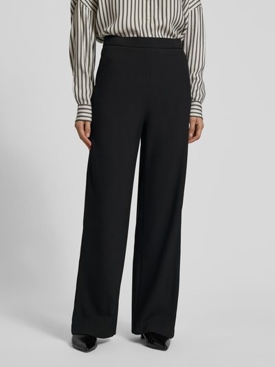 Frauenmodel trägt Wide Leg Stoffhose mit elastischem Bund Modell 'PALINA' von Raffaello Rossi, Material-Mix mit Viskose-Anteil, Crêpe-Struktur, französische Eingrifftaschen, Gesäßtaschen, schwarze Farbe, Ganzkörperansicht von vorne.