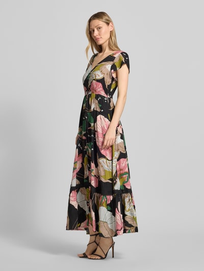 Frauenmodel trägt Maxikleid aus Viskose mit V-Ausschnitt von Apricot, florales Muster, Taillierte Passform, Volants, Eingrifftaschen, Ganzkörperansicht von vorne.