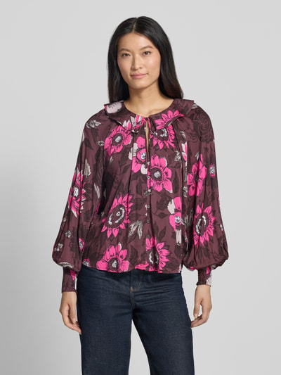Frauenmodel trägt Relaxed Fit Bluse aus reiner Viskose von Christian Berg Woman, floraler Allover-Print in Pink und Braun, Umlegekragen, Langarm, Ganzkörperansicht von vorne.