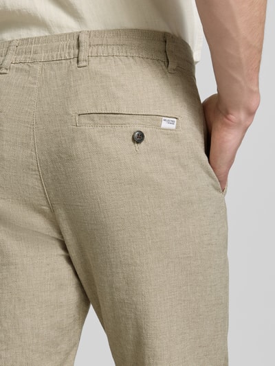 Männermodel trägt Regular Fit Hose aus Baumwoll-Leinen-Mix Modell 'BRODY' von SELECTED HOMME in Melange-Optik mit Label-Applikation, Detailaufnahme Rückansicht.