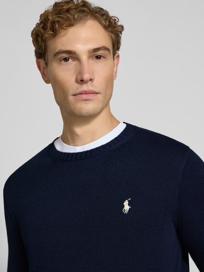 Männermodel trägt Relaxed Fit Pullover aus reiner Baumwolle von Polo Ralph Lauren in Dunkelblau mit feiner Strickstruktur, Nahaufnahme Oberkörper. Herren Pullover von Polo Ralph Lauren