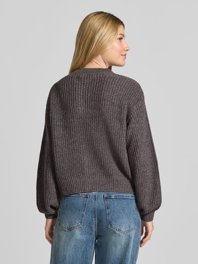 Frauenmodel trägt Loose Fit Strickjacke mit einreihiger Knopfleiste Modell 'LEA' von VERO MODA in Dunkelgrau zu blauen Jeans, Ganzkörperansicht Rückansicht. Damen Strickjacke von VERO MODA.