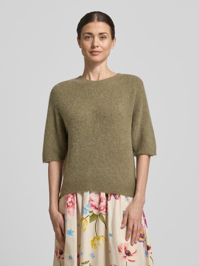 Vrouwenmodel draagt gebreide pullover met 1/2-mouwen van Oui, materiaalmix met alpacawol, regular fit, ronde hals, ruglengte 54 cm, mouwlengte 34 cm, kleur olijfgroen, zachte textuur, bloemenrok, Ganzkörperansicht von voren.