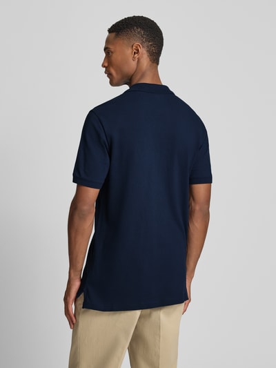 Männermodel trägt Slim Fit Poloshirt mit Label-Stitching von GAP, dunkelblau, Baumwoll-Elasthan-Mix, Rückenlänge 70 cm, Ganzkörperansicht Rückansicht.