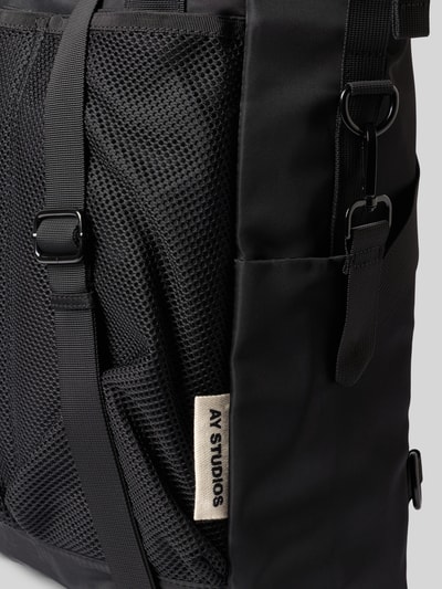 Produktfoto, Rucksack mit Logo-Detail von AY STUDIOS in Schwarz, Netz-Tasche, glatte und grobe Texturen, dezenter Marken-Schriftzug, Kontext: Herren Rucksack, Hauptfach mit Reißverschluss, verstellbare Schulterriemen, 42 cm breit, 54 cm lang, 13 cm tief, Schulterriemen 98 cm, KI-modifiziertes Bild
