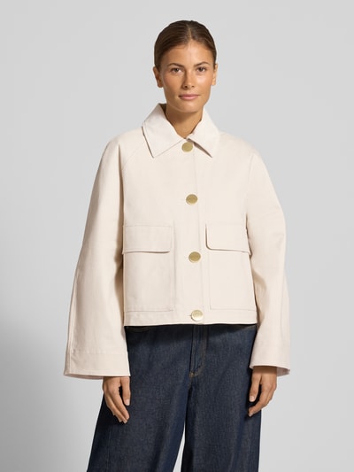 Frauenmodel trägt Jacke mit Pattentaschen von Armani Exchange in Creme, Baumwoll-Elasthan-Mix, goldene Knöpfe, Ganzkörperansicht von vorne.