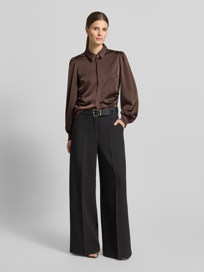 Modelka nosi Bluzka koszulowa Regular Fit Hemdbluse mit Raffungen Modell 'Fransala' od Neo Noir, elastyczna mieszanka materiałów, kołnierzyk koszulowy, z długim rękawem, marszczenia, obszycie ozdobnymi kamieniami, wykończone rękawy, długość tyłu 55 cm, długość rękawa 65 cm, widok całej sylwetki z przodu.