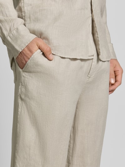 Männermodel trägt Leinenhose mit elastischem Bund van MCNEAL in licht beige, regular fit, zuiver linnen met tunnelkoord, detailaufnahme heup.