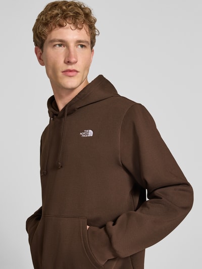 Mannelijk model draagt Regular Fit Hoodie met kangoeroezak Model "EVOLUTION" van The North Face in katoenmix, logostitching, schouder- en mouwdetails, kleur bruin, Nahaufnahme Oberkörper.