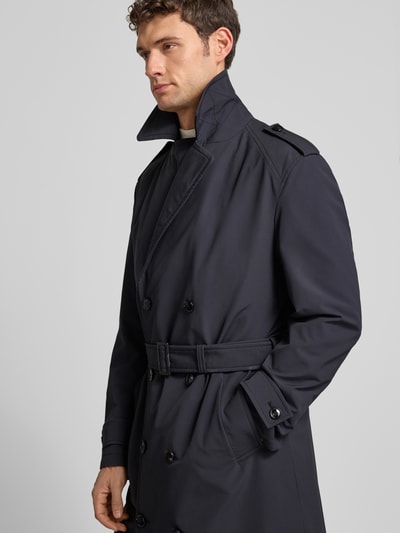 Männermodel trägt Regular Fit Trenchcoat mit Taillengürtel Modell 'TRENCH SUMMER' von Strellson in Unifarben mit Label Patch, Nahaufnahme Oberkörper.