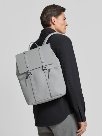 Männermodel trägt Rucksack mit Logo-Detail Modell 'SPLÄSH 2.0' von GASTON LUGA in lichtgrijs met overslag, verstelbare schouderband, hoofdvak, Breedte 38 cm, Lengte 40 cm, Diepte 12 cm, bandlengte 80 cm, Ganzkörperansicht Rückansicht